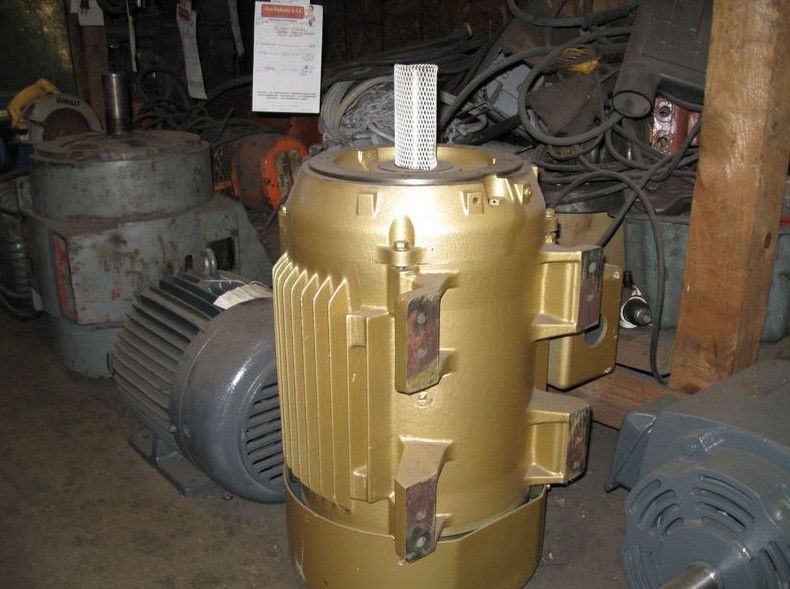 A large gold motor is sitting in a warehouse surrounded by other motors