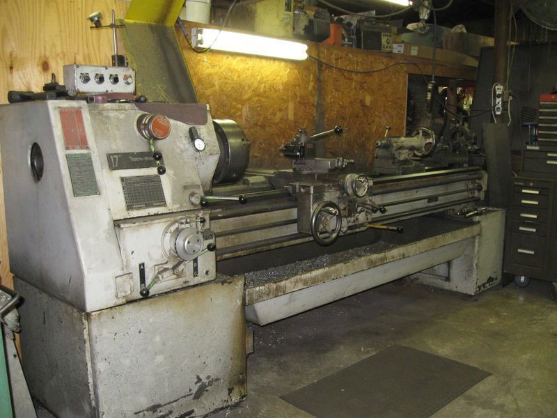 A lathe is sitting in a garage next to a cabinet