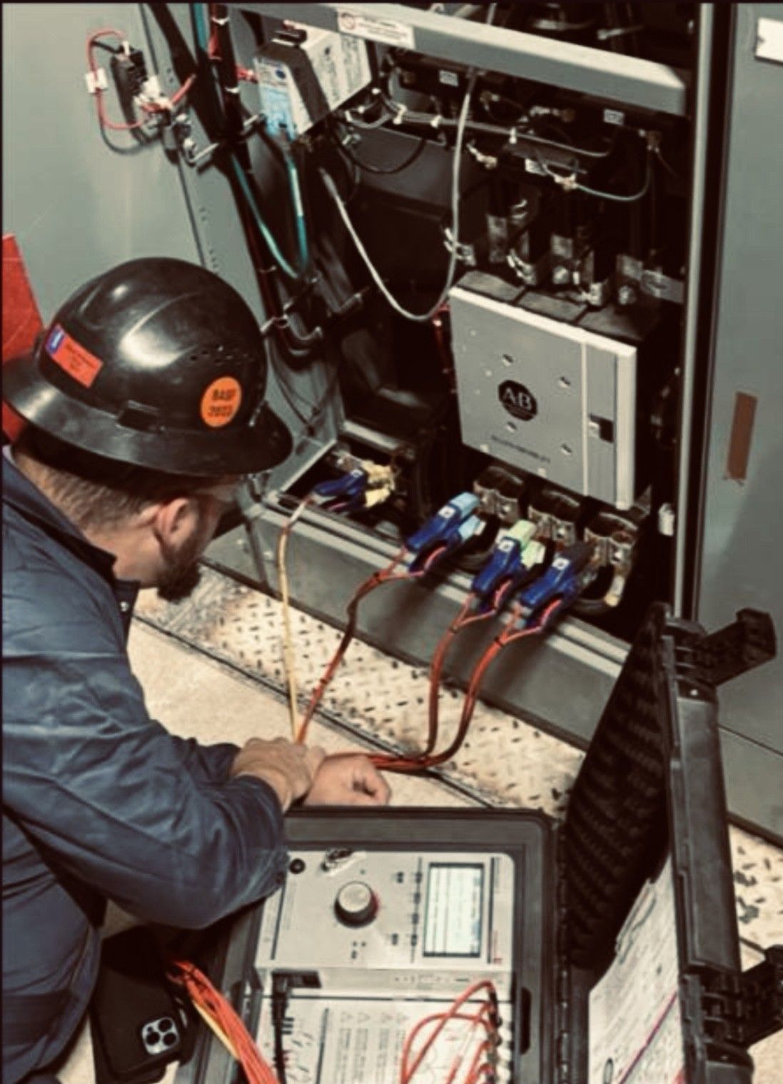 A man wearing a hard hat is working on an electrical box