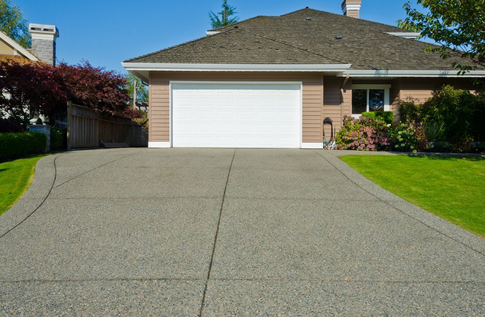 A Driveway Leading To A House With A White Garage Door — Concept Concreting NSW In Figtree, NSW