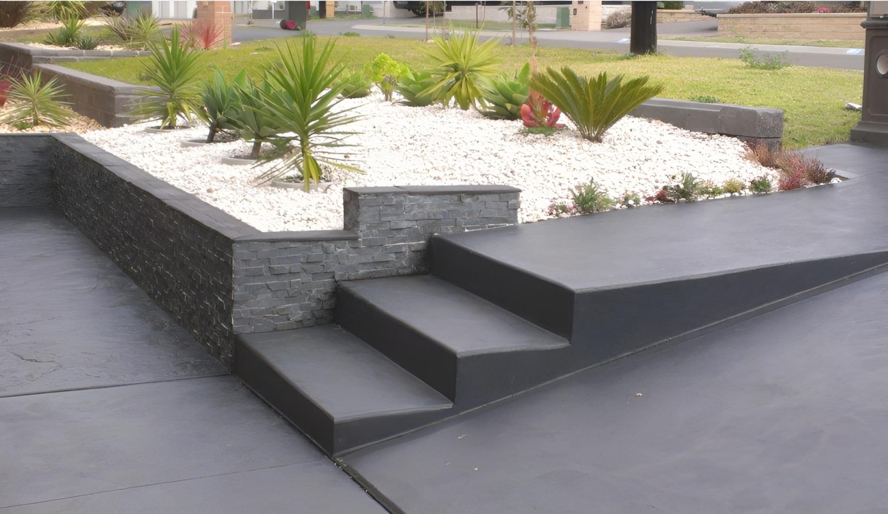 A Black Driveway With Steps Leading Up To A Garden — Concept Concreting NSW In Figtree, NSW