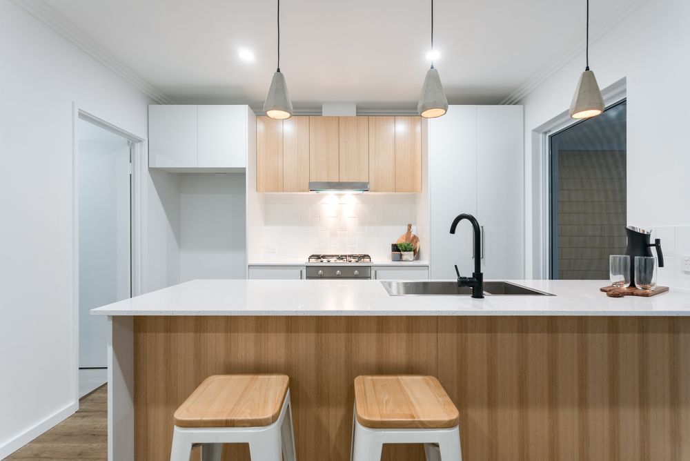 A Kitchen With a Large Island and Two Stools — Hunter Kitchen King In Morriset, NSW
