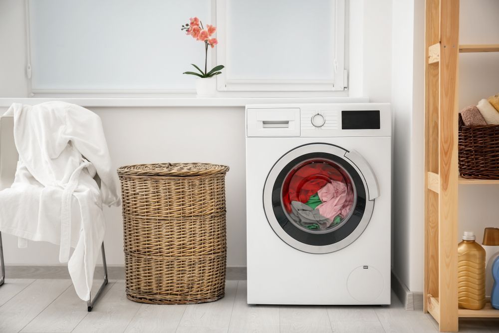 A Washing Machine is Sitting in a Laundry Room Next to a Wicker Basket — Hunter Kitchen King In Port Stephens, NSW