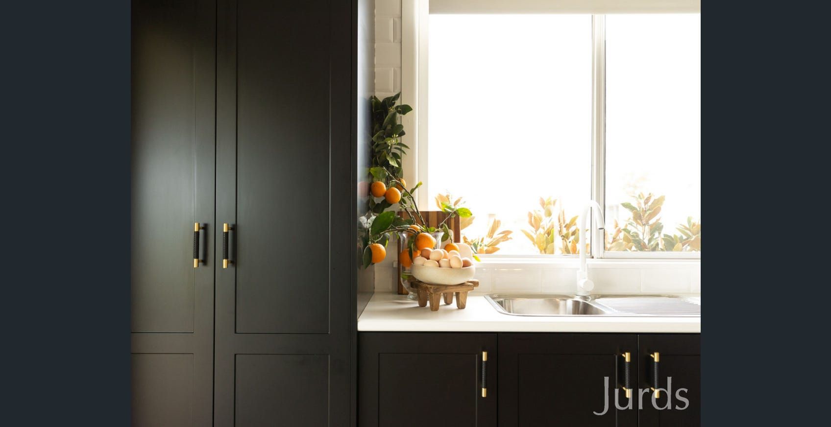 An Empty Kitchen With White Cabinets and a Large Island — Hunter Kitchen King In Rutherford, NSW