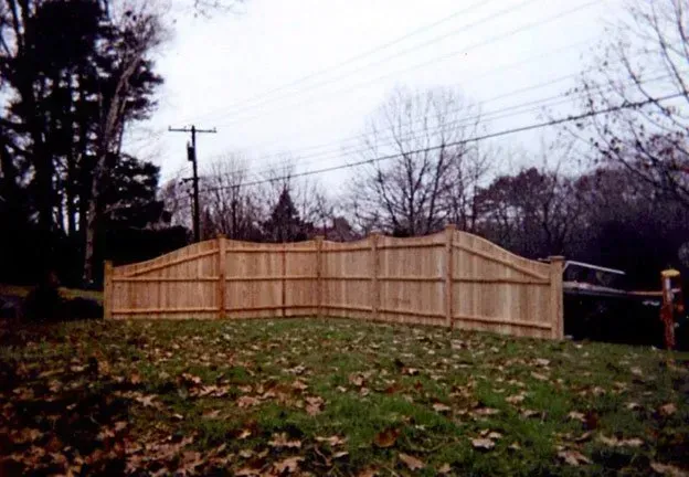 A wooden fence is in the middle of a grassy field.