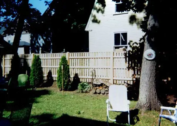 A backyard with a white fence and chairs