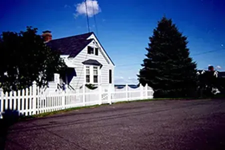 A white house with a white picket fence in front of it.