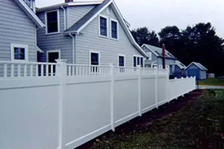 There is a white fence in front of a house.