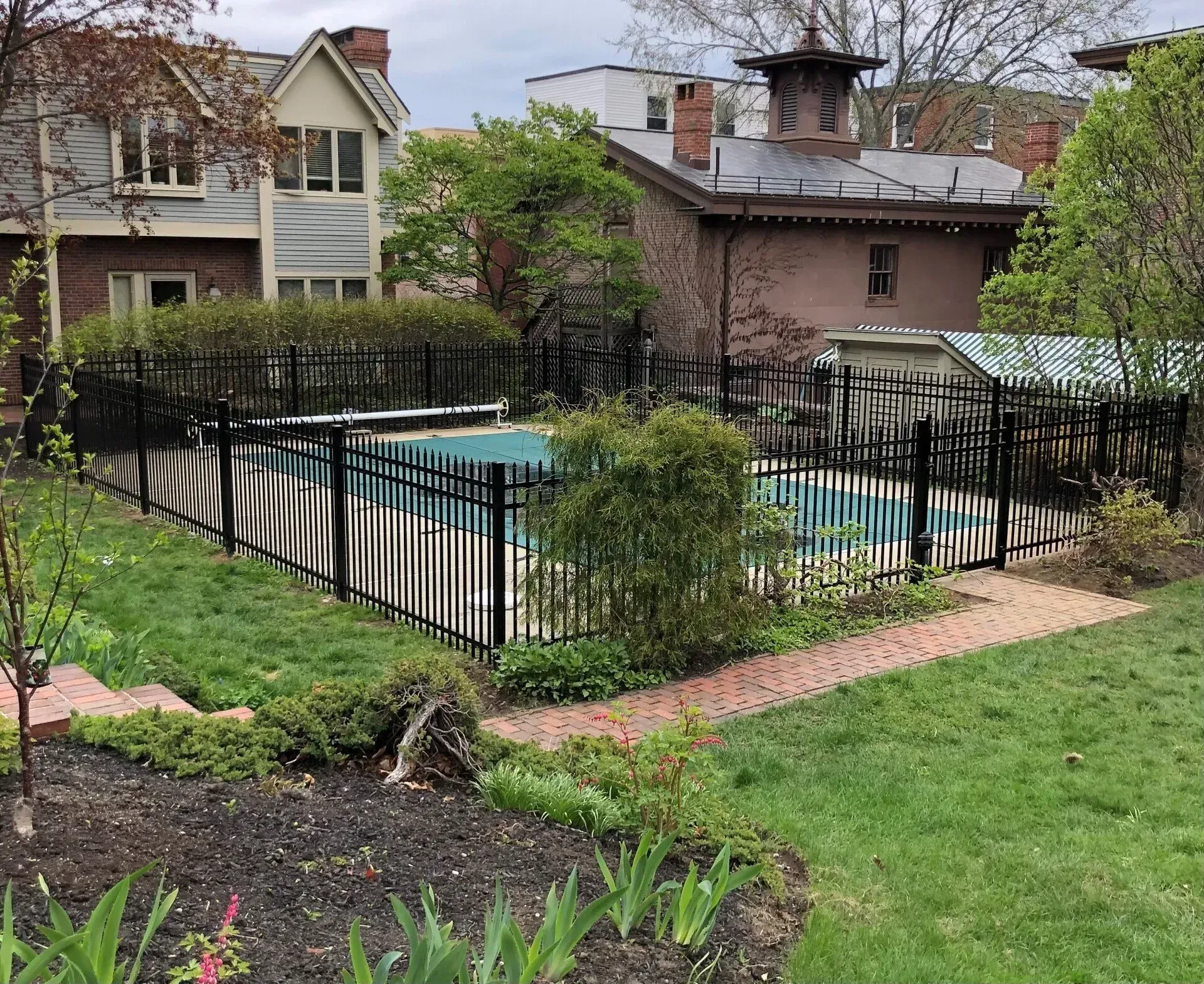 A fence surrounds a swimming pool in a backyard
