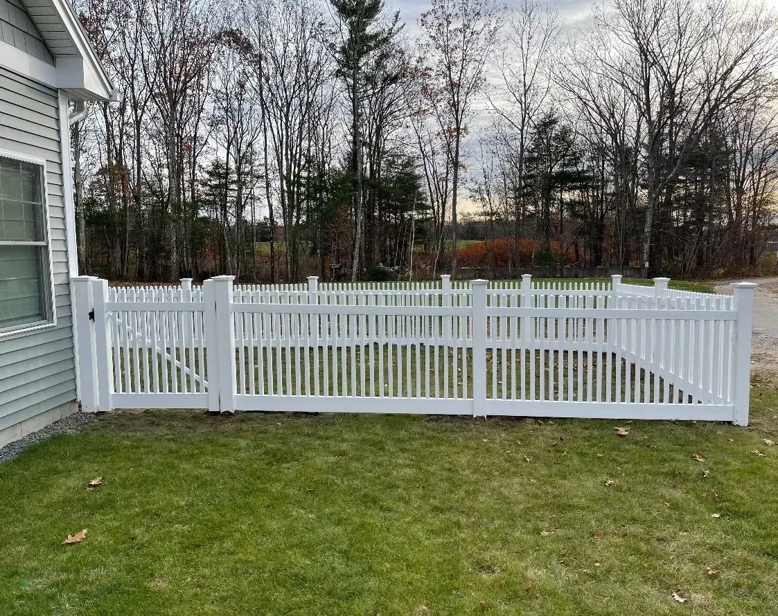 A white fence is sitting in front of a house.