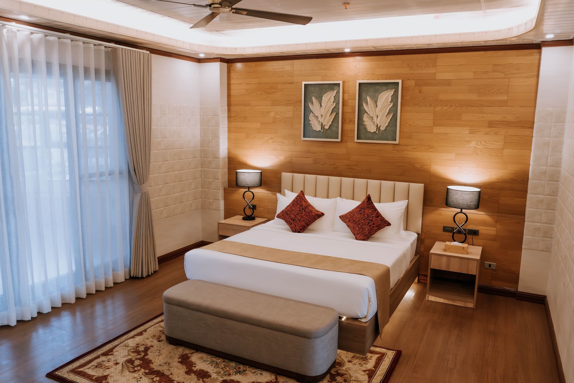 Bedroom with bed, nightstands, wood paneling, artwork, and window with curtains.