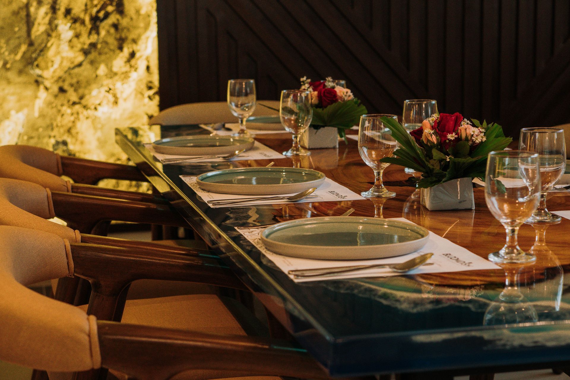 A dining table set for guests with plates, glasses, and floral arrangements.