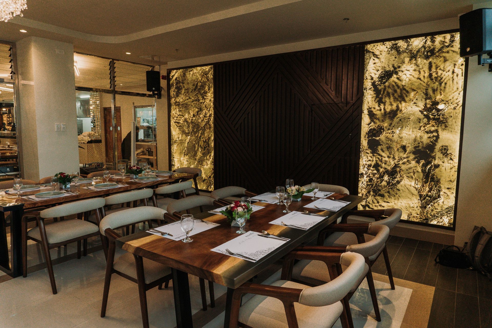 Elegant restaurant interior with long wooden tables set for diners, adorned with floral centerpieces.