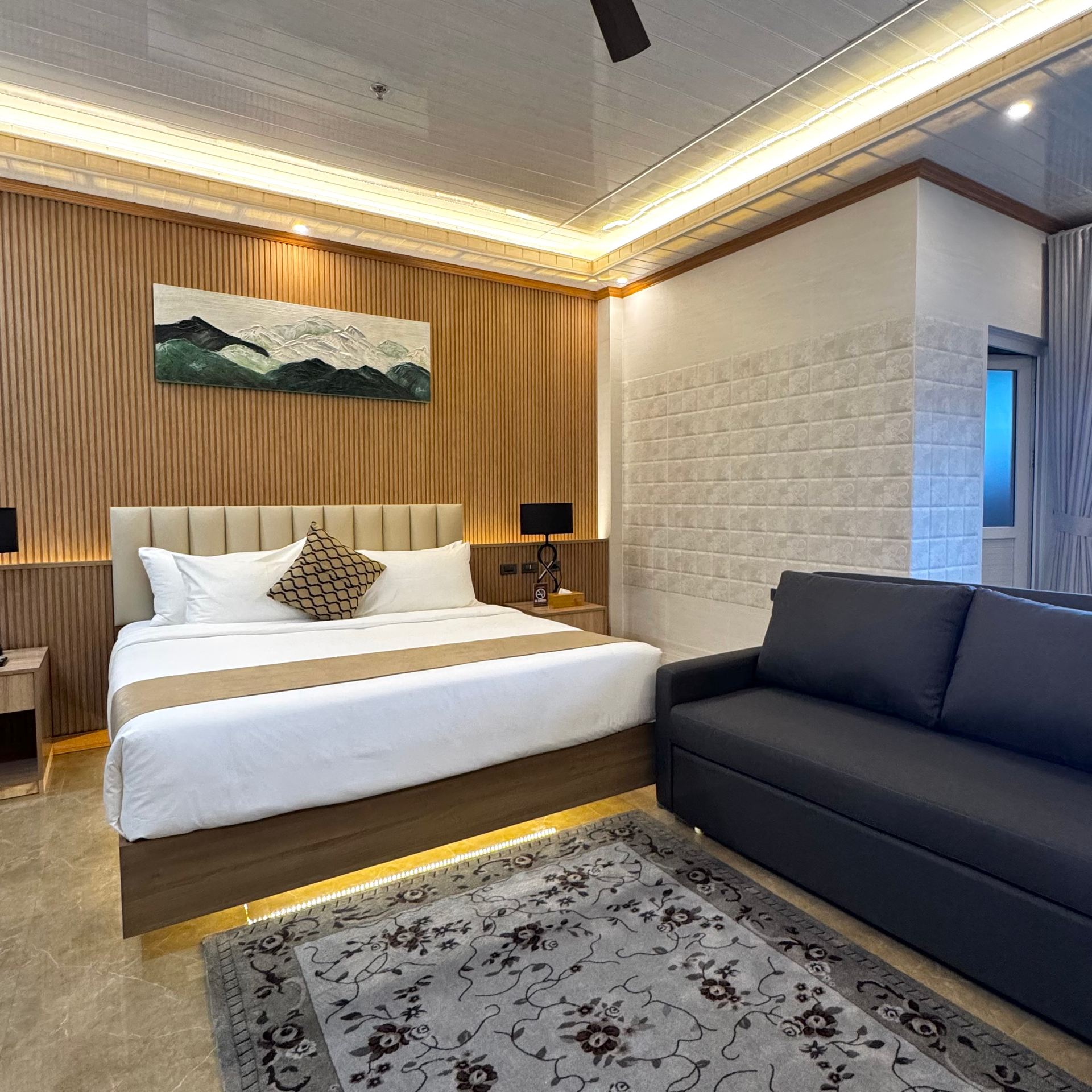 Bedroom with bed, art, wood paneling, lamps, nightstands, and rug.