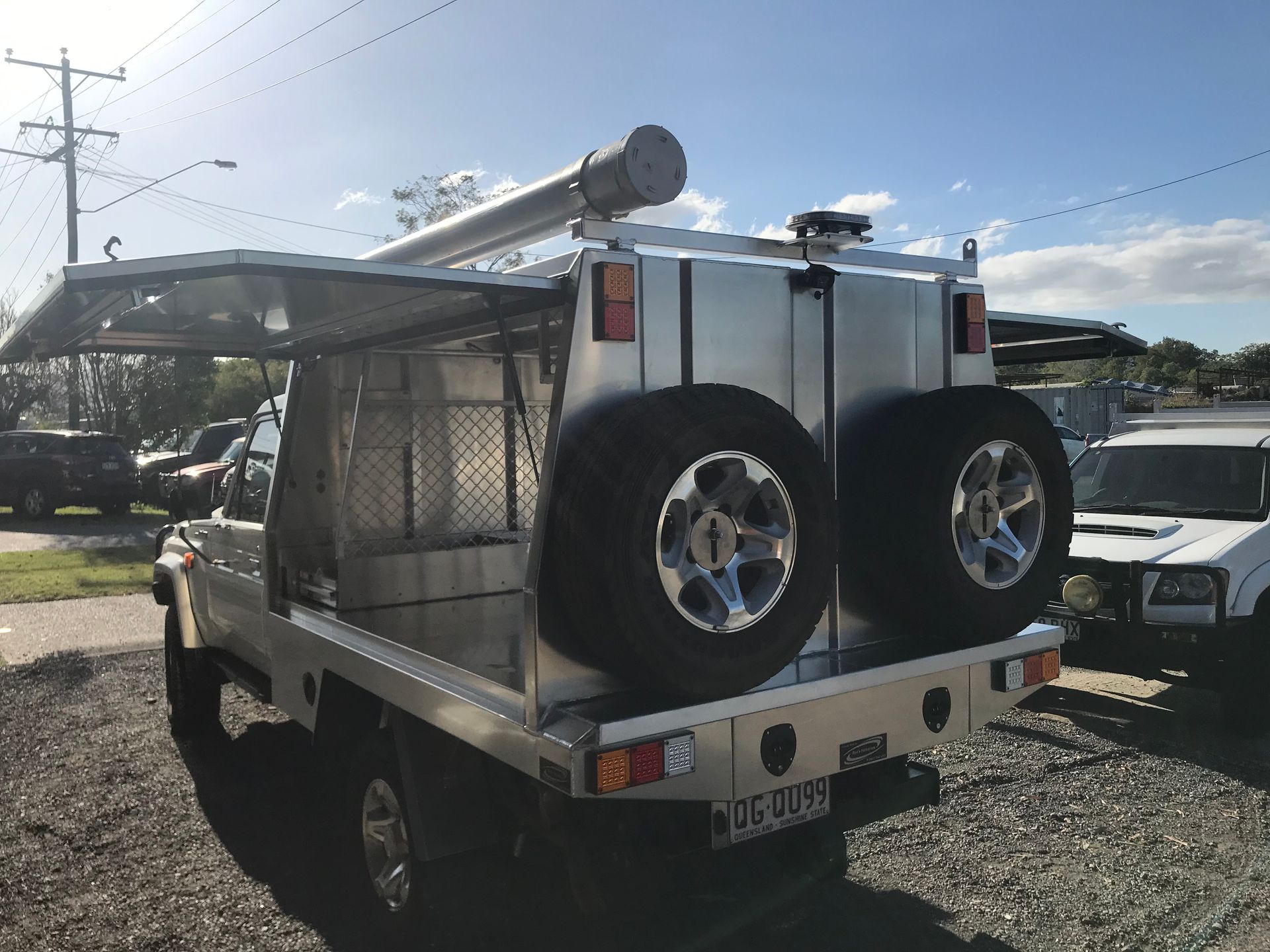 Silver work truck with spare tires, awning, and storage compartments.— Boyd's Fabrications In Portsmith, QLD 