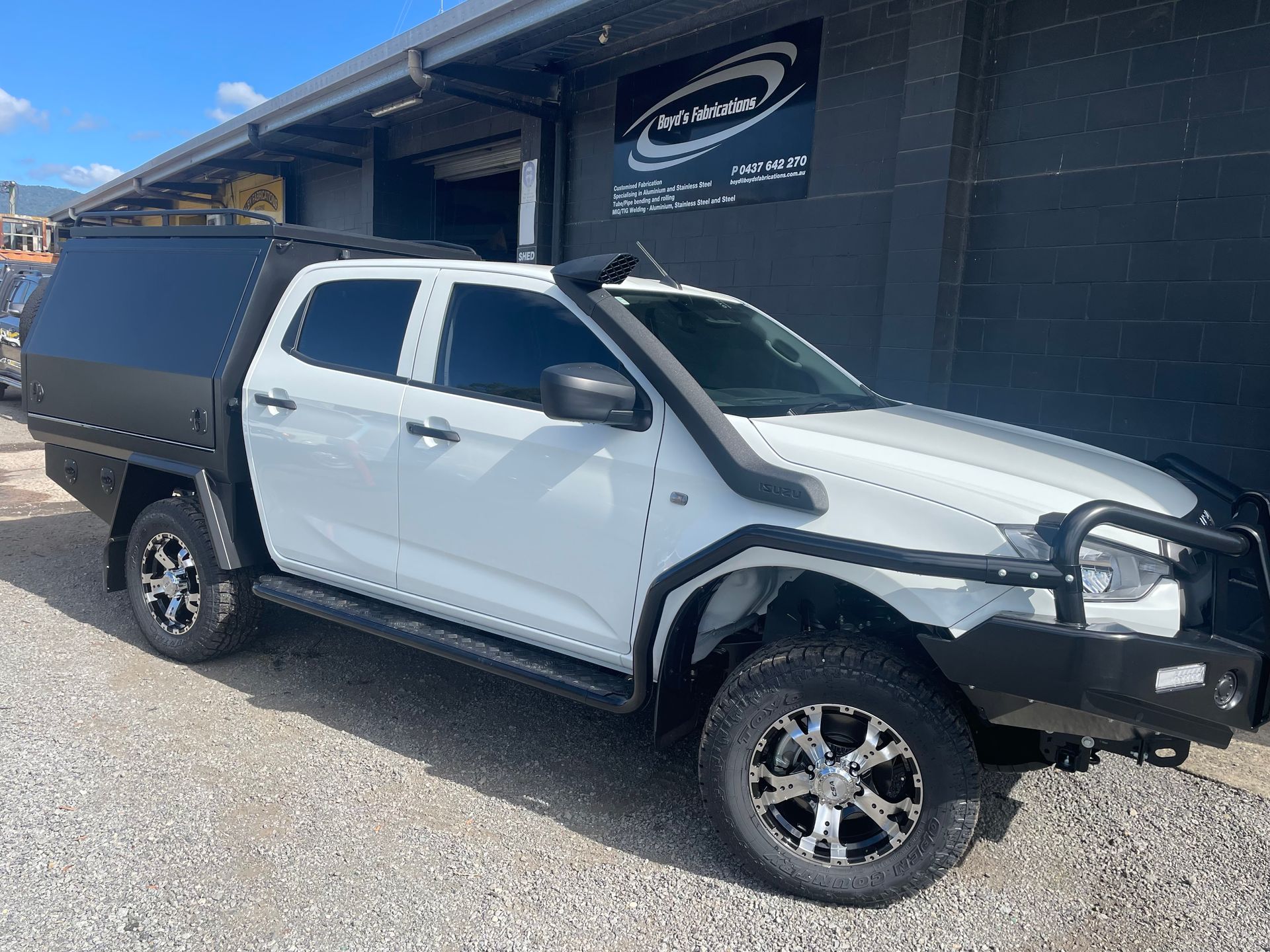 White pickup truck with black canopy, bull bar, snorkel, and custom wheels parked in front of a building.— Boyd's Fabrications In Portsmith, QLD 