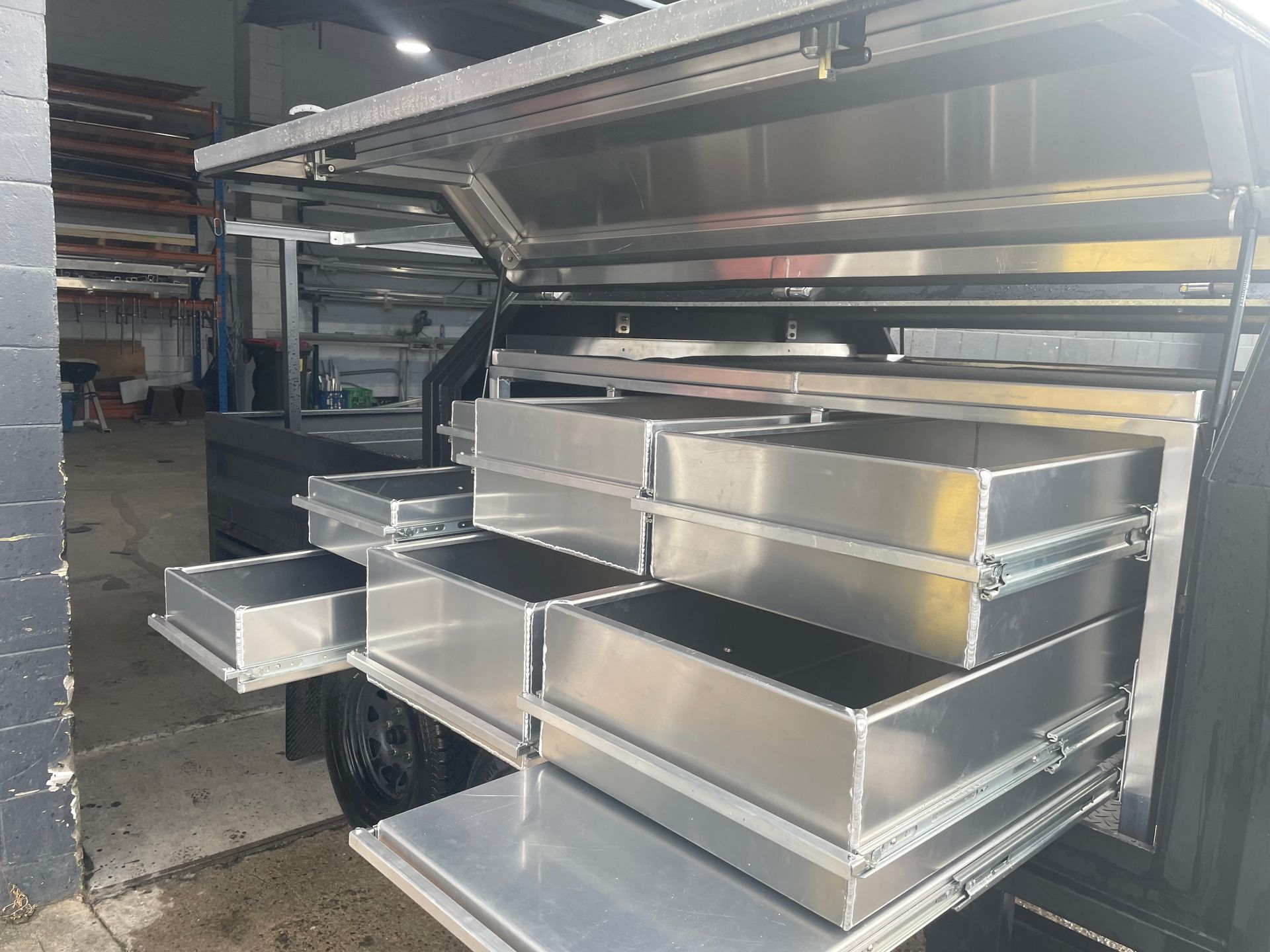 Open storage drawers in a truck bed. Silver metal drawers are pulled out, revealing storage space.— Boyd's Fabrications In Portsmith, QLD 