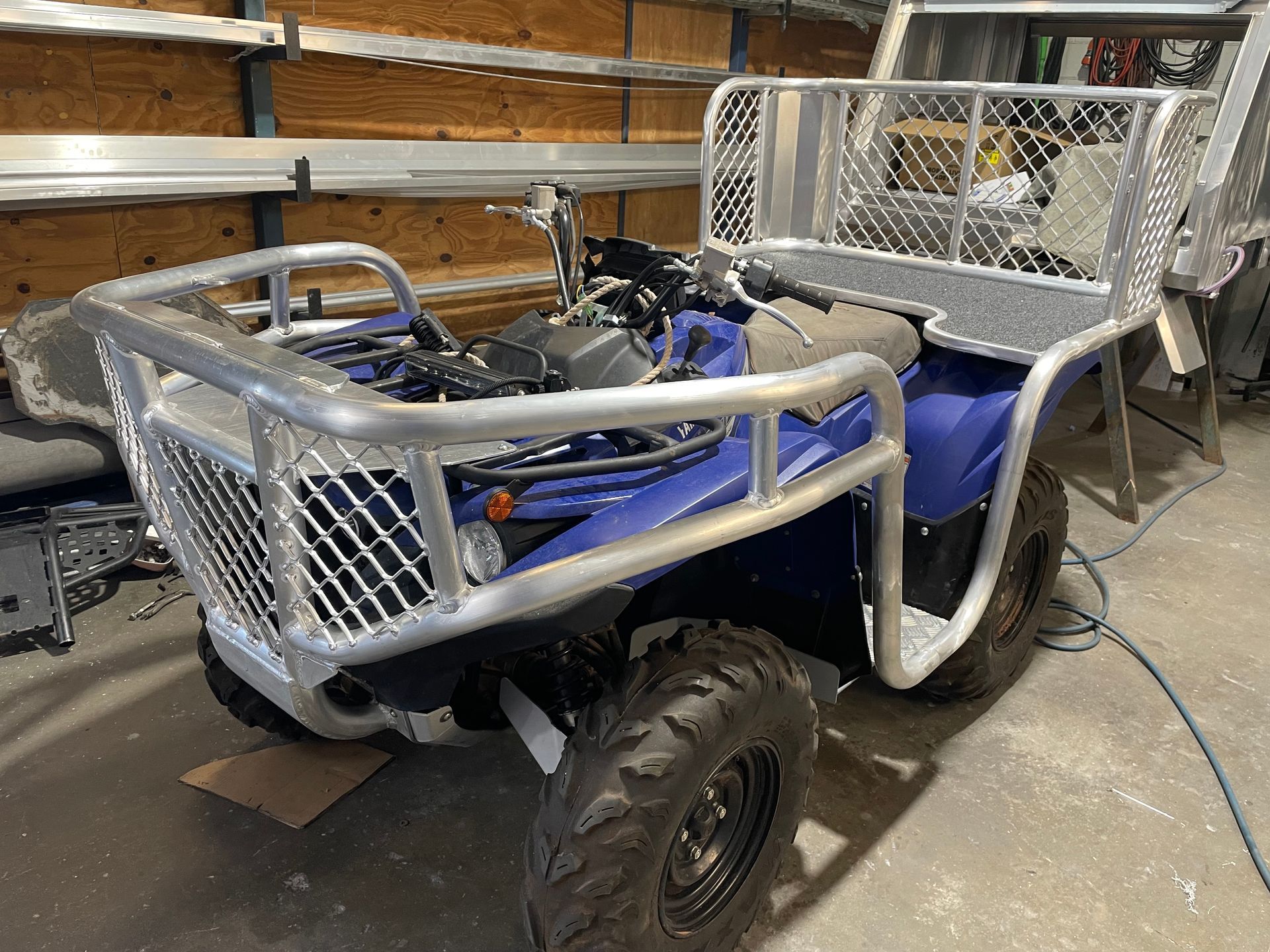Blue ATV with custom aluminum front guard and cargo bed in a workshop.— Boyd's Fabrications In Portsmith, QLD 