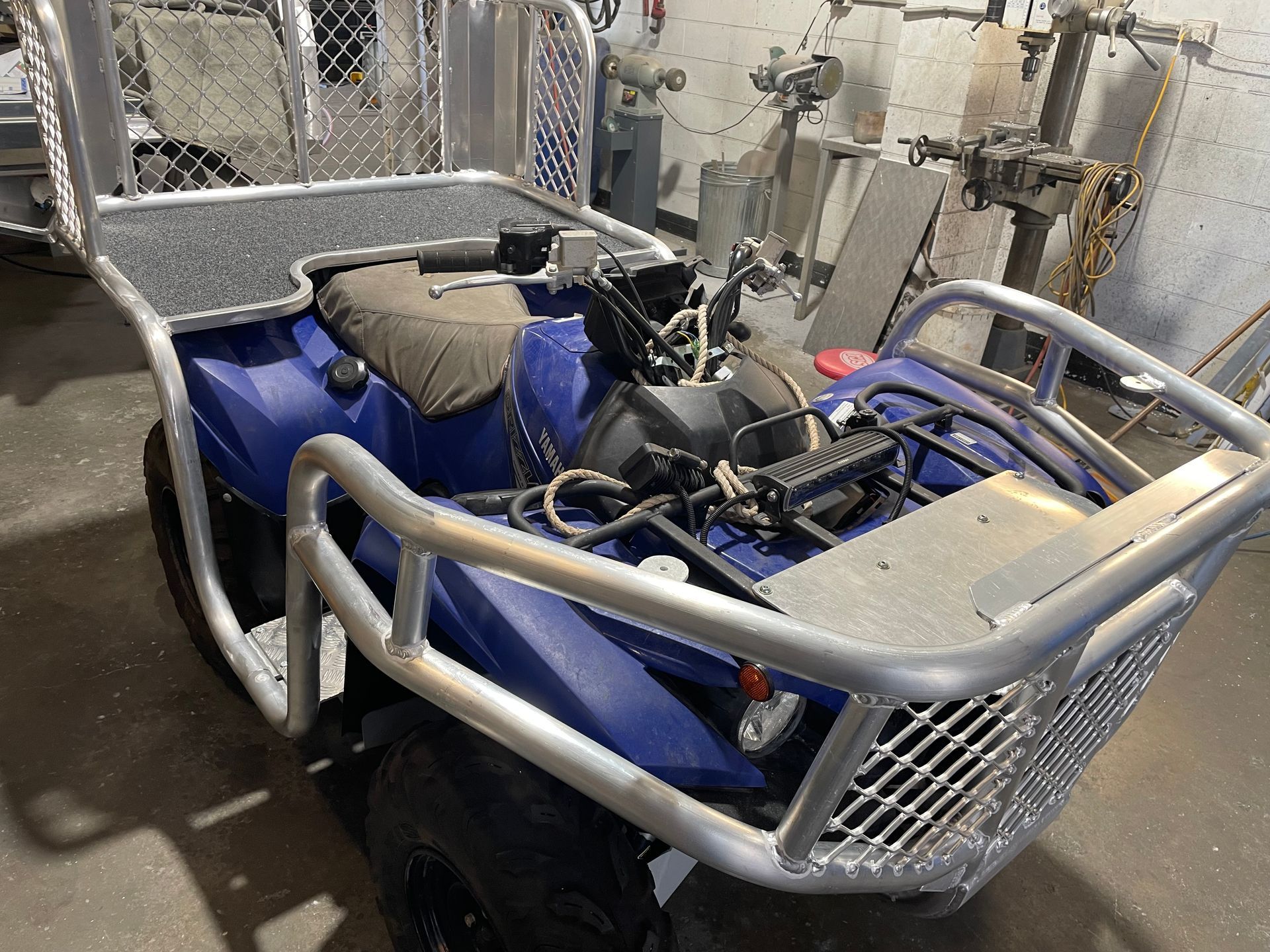 Blue ATV with silver roll cage and cargo rack, in a workshop.— Boyd's Fabrications In Portsmith, QLD 