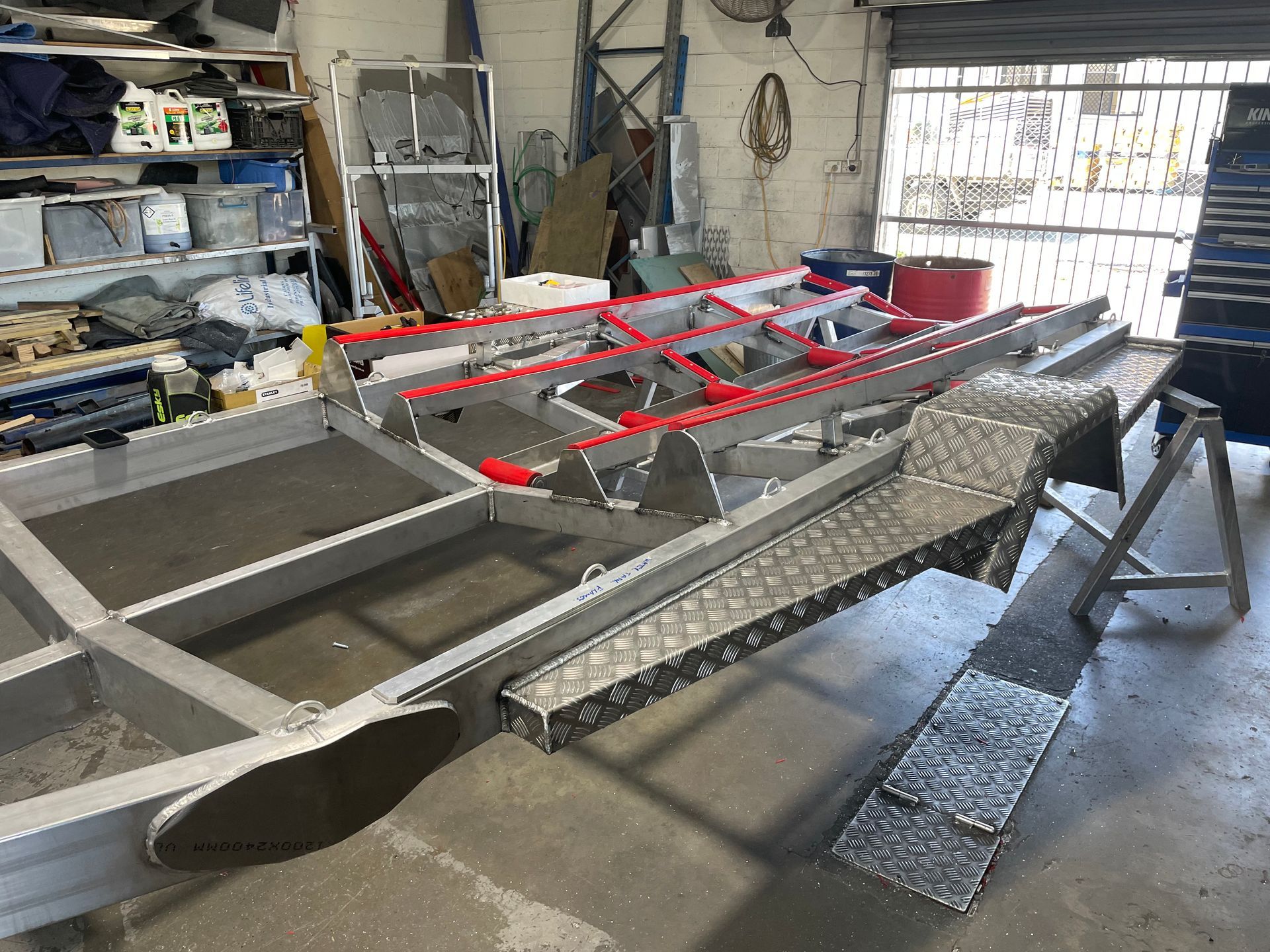 Aluminum boat frame under construction in a workshop, with red accents and diamond plate detailing.— Boyd's Fabrications In Portsmith, QLD 