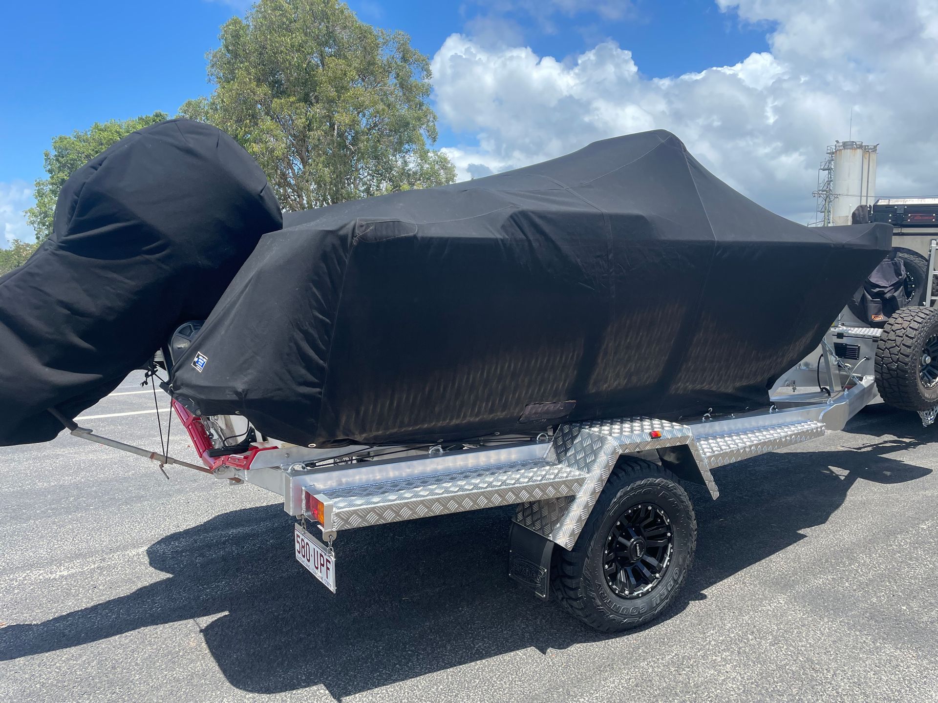 Boat on trailer, covered in black, parked outdoors.— Boyd's Fabrications In Portsmith, QLD 