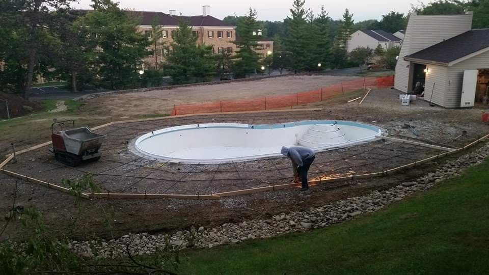 A man is working on a swimming pool in a backyard.