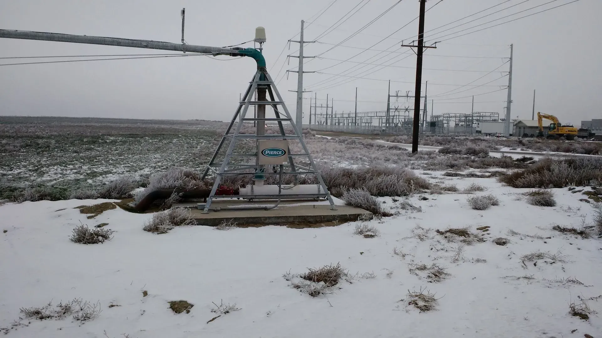 A sprinkler is sitting in the middle of a snowy field