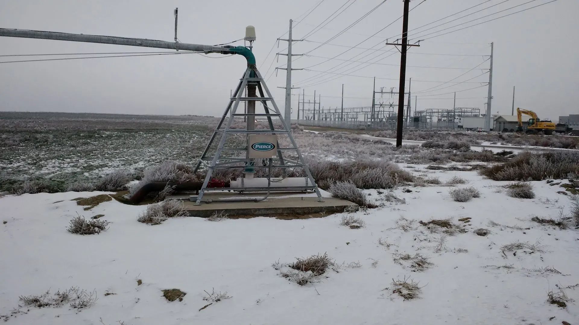 Snowy landscape with an irrigation system and power lines.