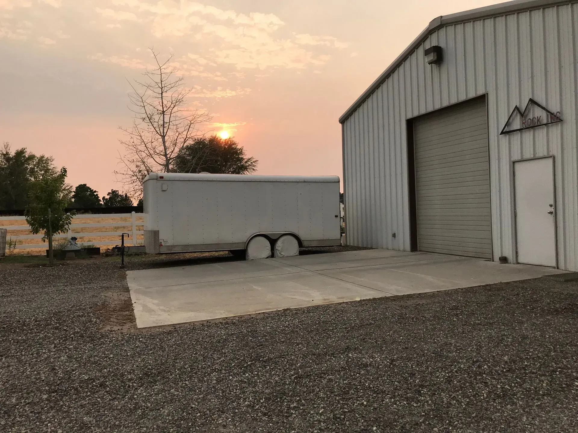 A white trailer is parked in front of a white building.