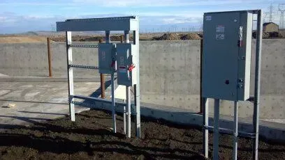 A row of electrical boxes sitting on top of a dirt field.