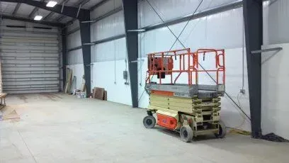 A scissor lift is parked in an empty warehouse.