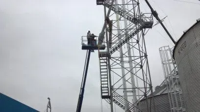 A man is standing on a crane working on a metal structure.