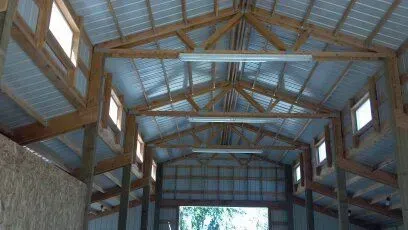The inside of a large building with wooden beams and a metal roof.