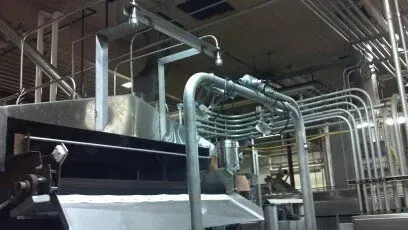 A factory with a lot of pipes hanging from the ceiling.