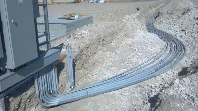 A bunch of electrical wires are laying in the dirt.