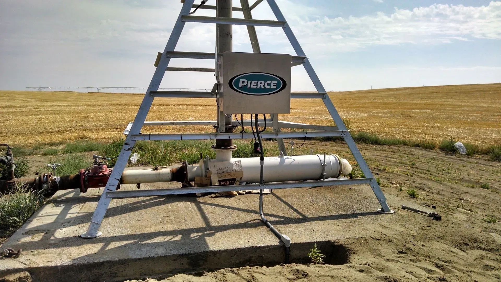 Irrigation pump station, Pierce equipment, in a field with dry vegetation.