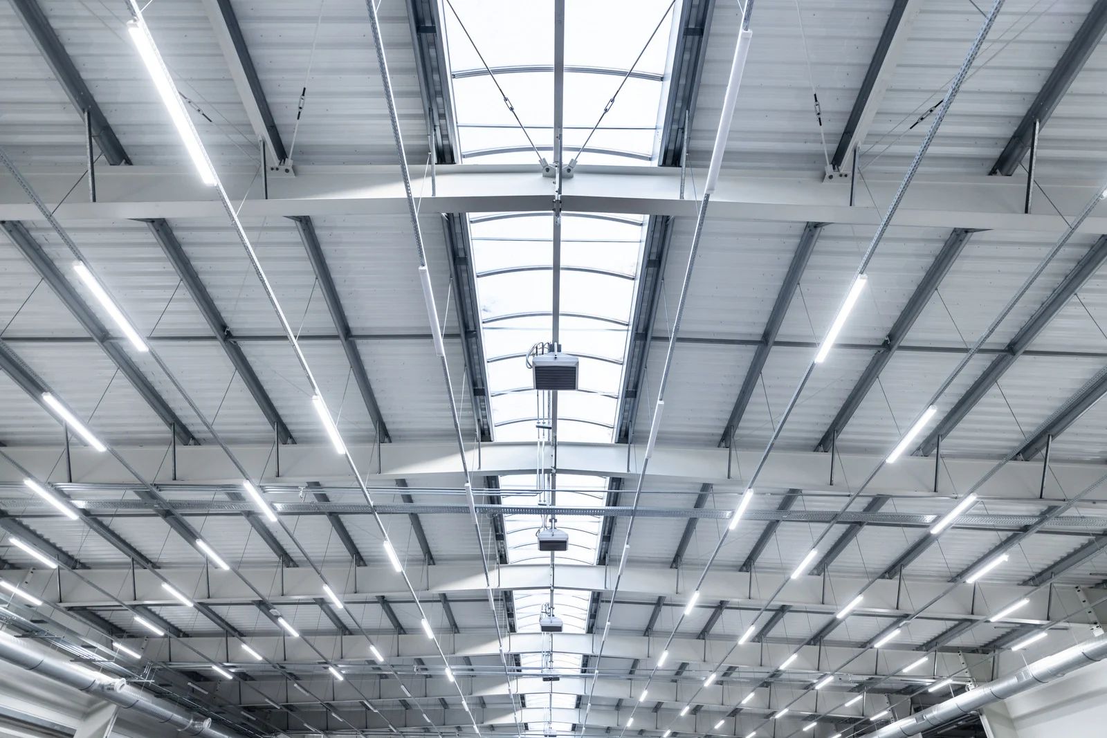 Warehouse interior with metal roof, skylights, and bright overhead lights.