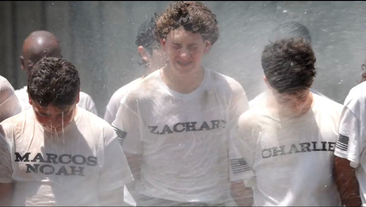 A group of young men wearing white shirts with the names marcos and charlie on them are standing in a room.