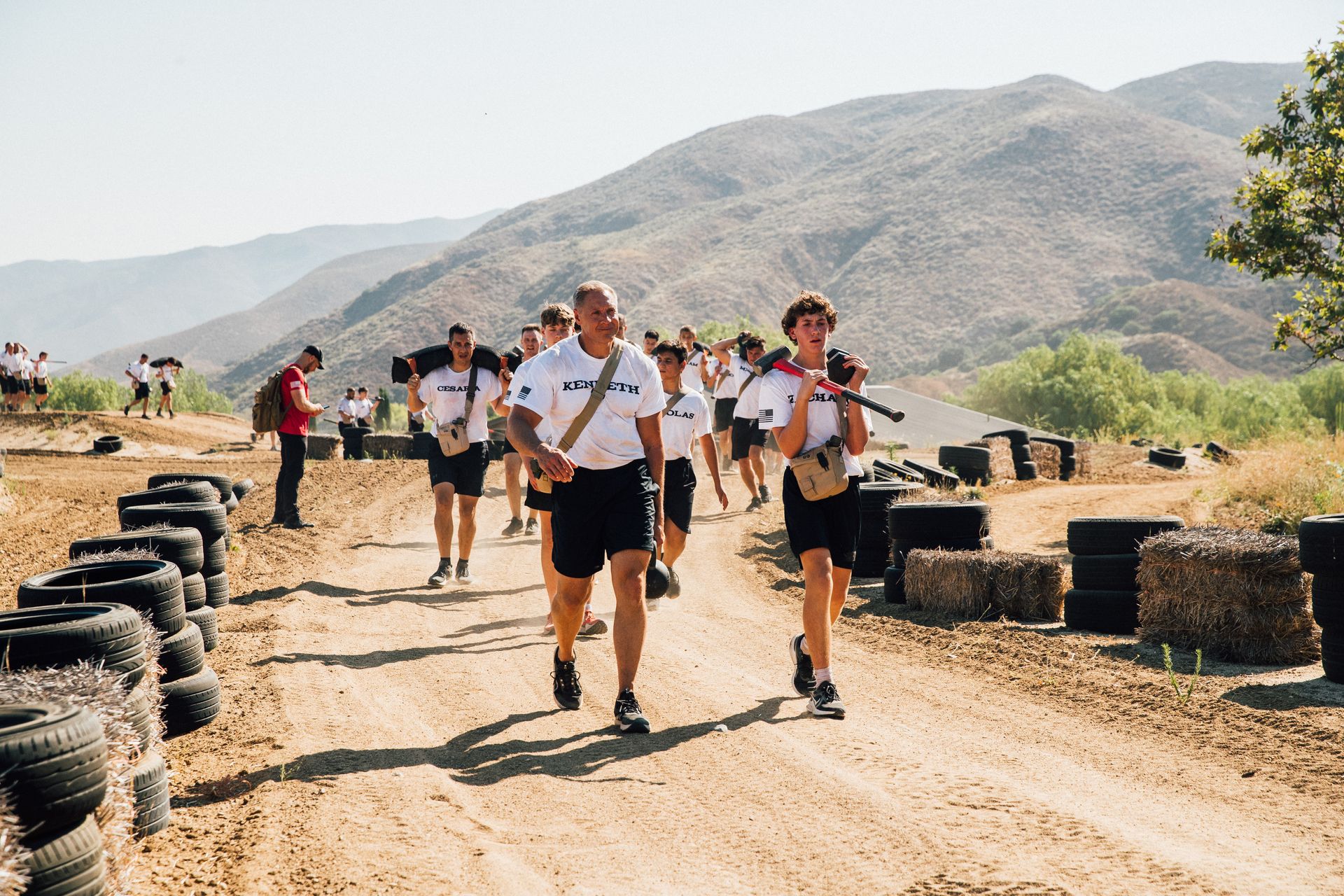 A group of people are walking down a dirt road.