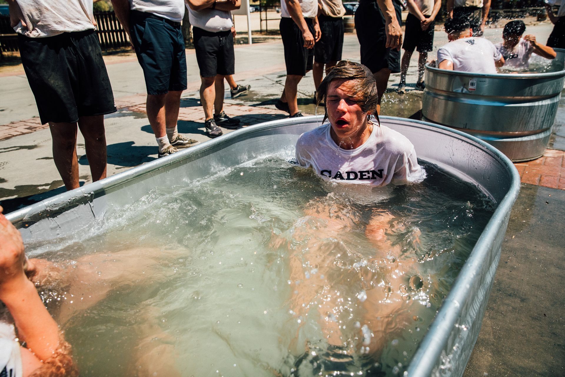 A group of people are standing around a metal tub filled with water.