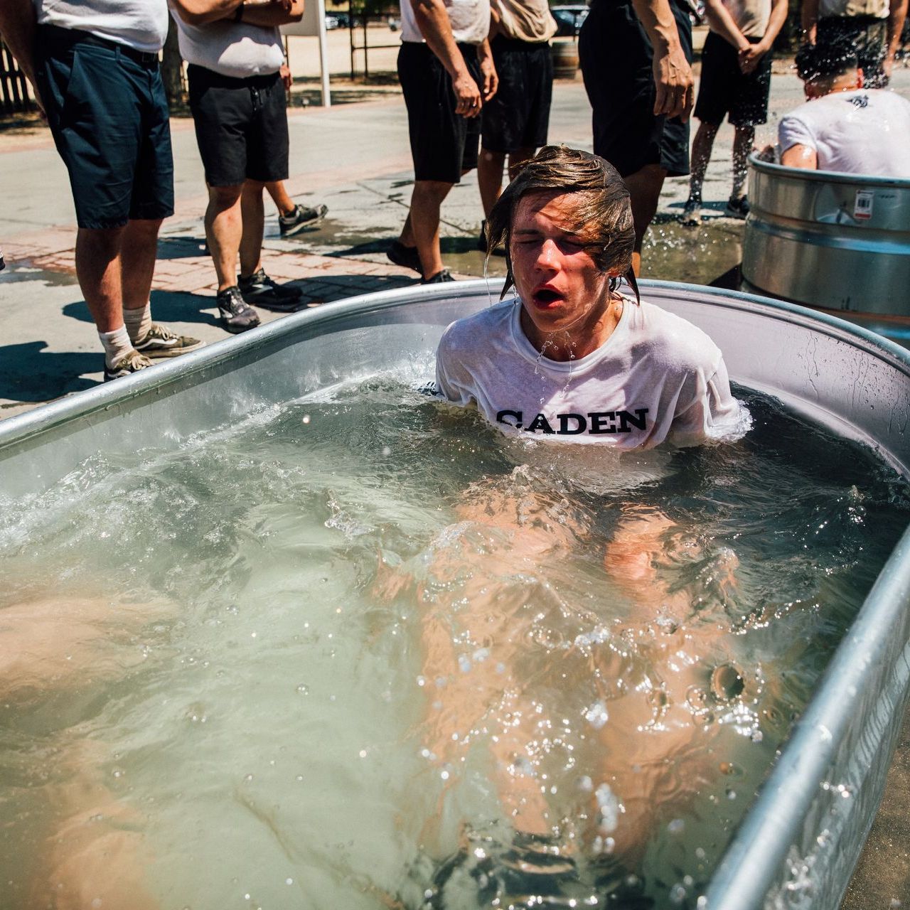 A man in a saden shirt is in a tub of water