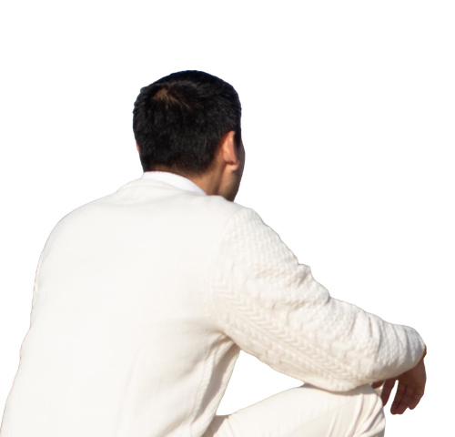 A man in a white sweater sits on a white surface