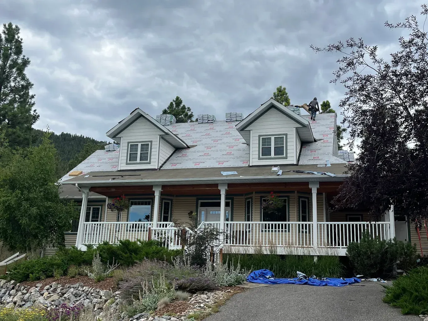 House with exposed roof during renovation, porch, overcast sky.
