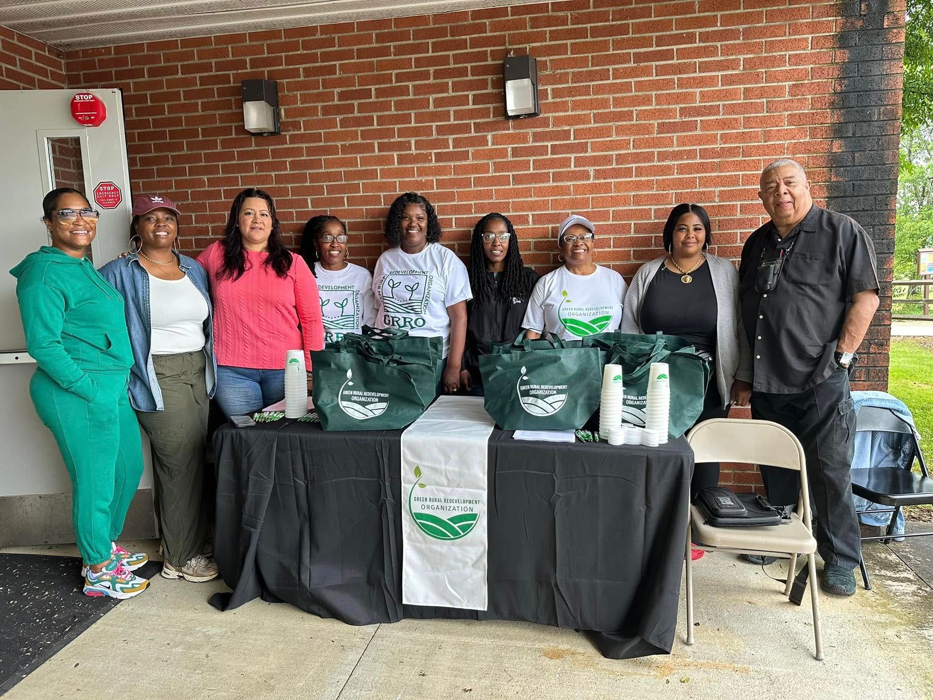 A group of people standing around a table with bags on it.