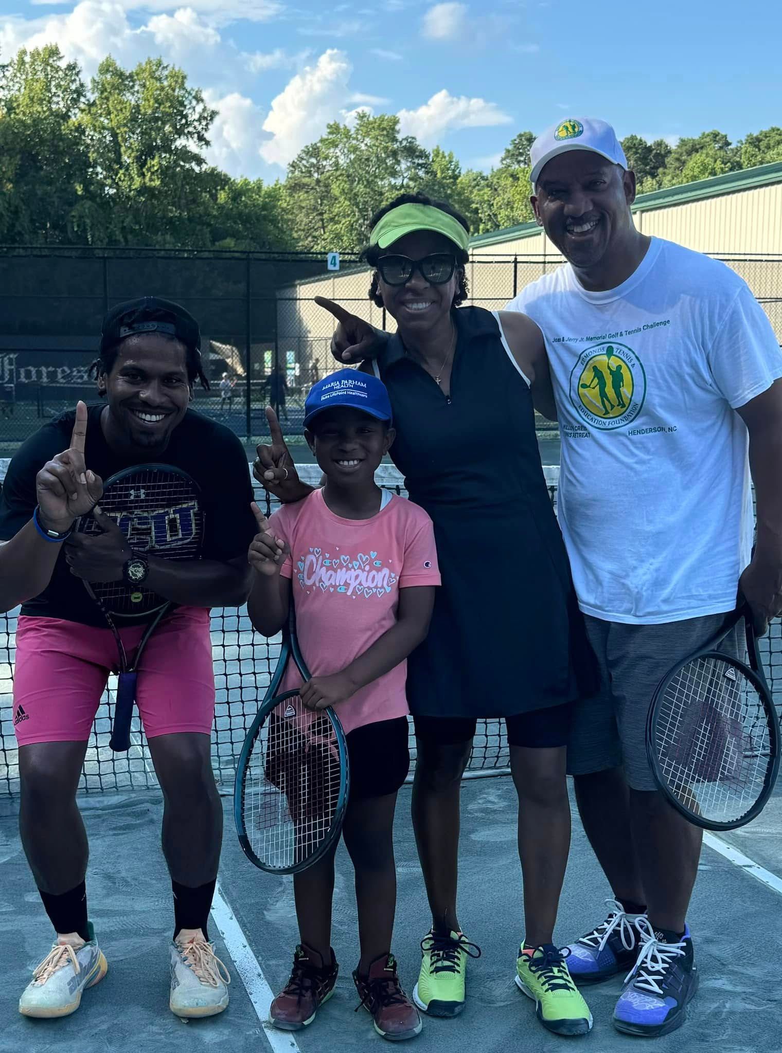 A group of people are posing for a picture on a tennis court.