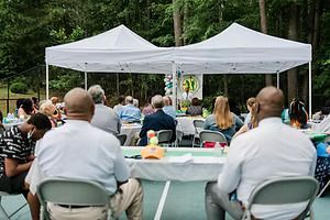A group of people are sitting at tables under tents.