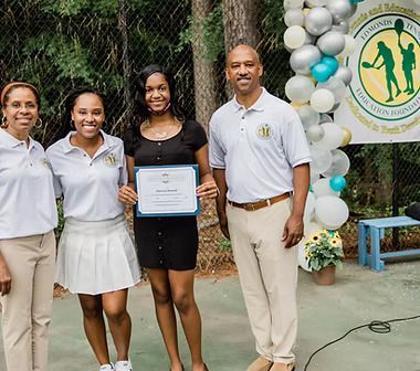 A group of people are posing for a picture on a tennis court.