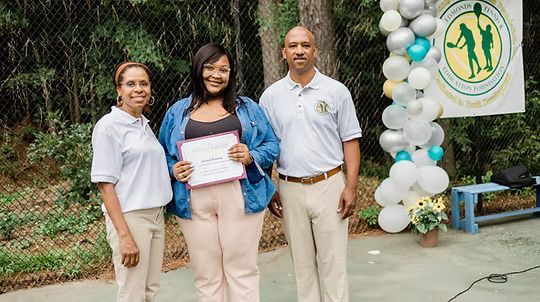 A woman is holding a certificate while standing next to two men.