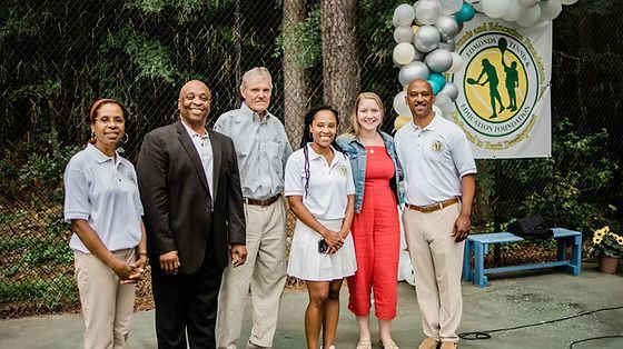 A group of people are standing next to each other in front of a sign.