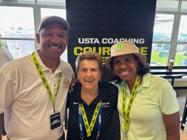 Three smiling people pose for a photo at a USTA coaching event.